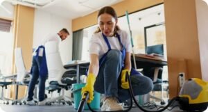 Mitarbeiterin reinigt Büroteppich mit Dampfreiniger für allergenfreie, hygienische Arbeitsräume.